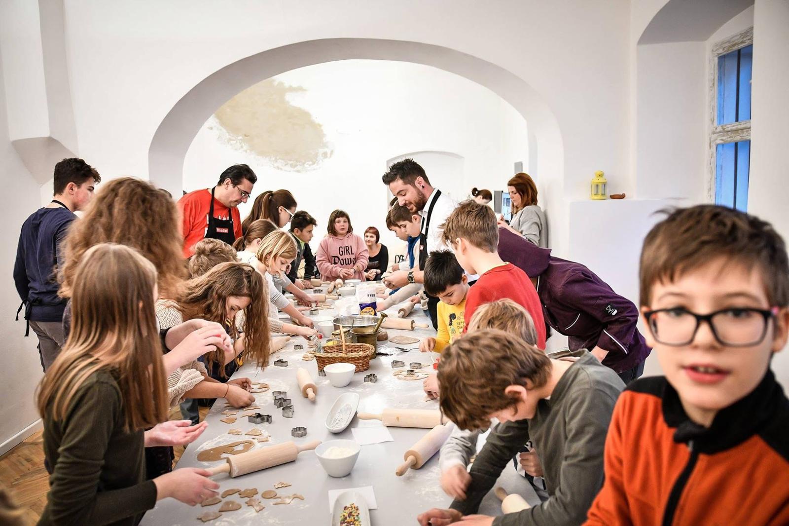 Kids gathered around a long table baking together under a vaulted arch