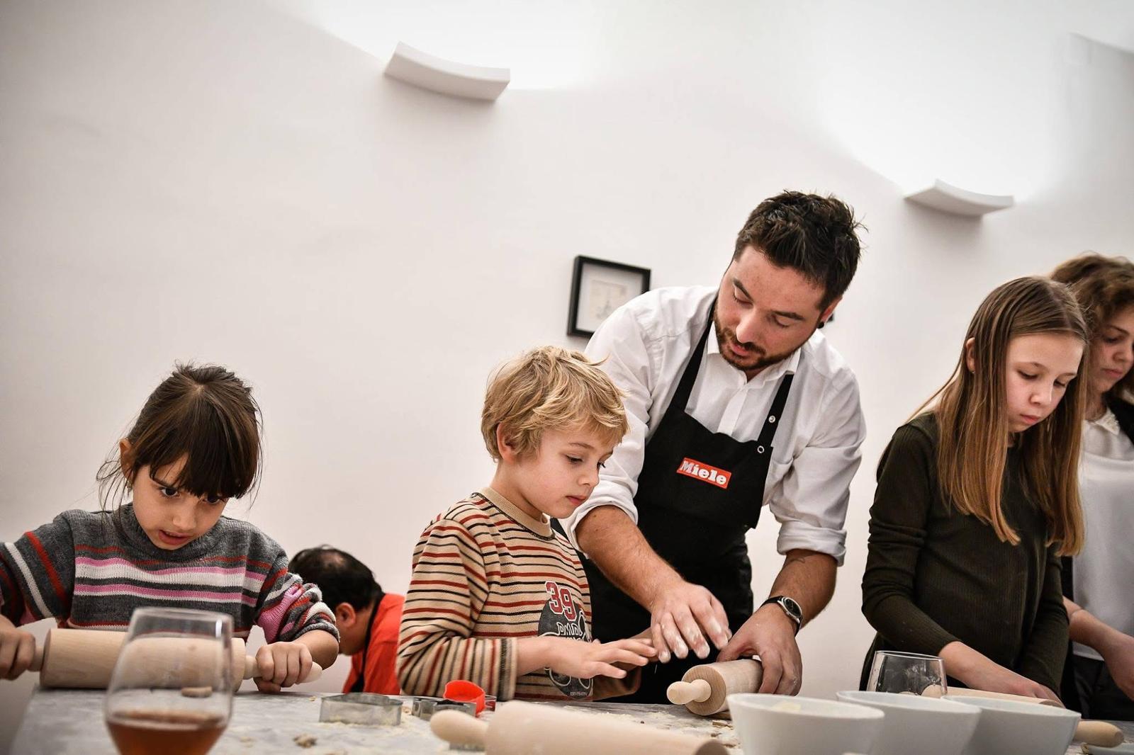 Chef teaching a young child how to roll out dough at a workshop